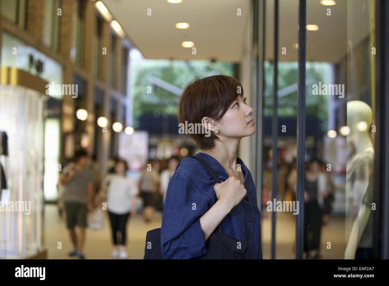 Una donna in un centro commerciale alla ricerca di un negozio window display. Foto Stock