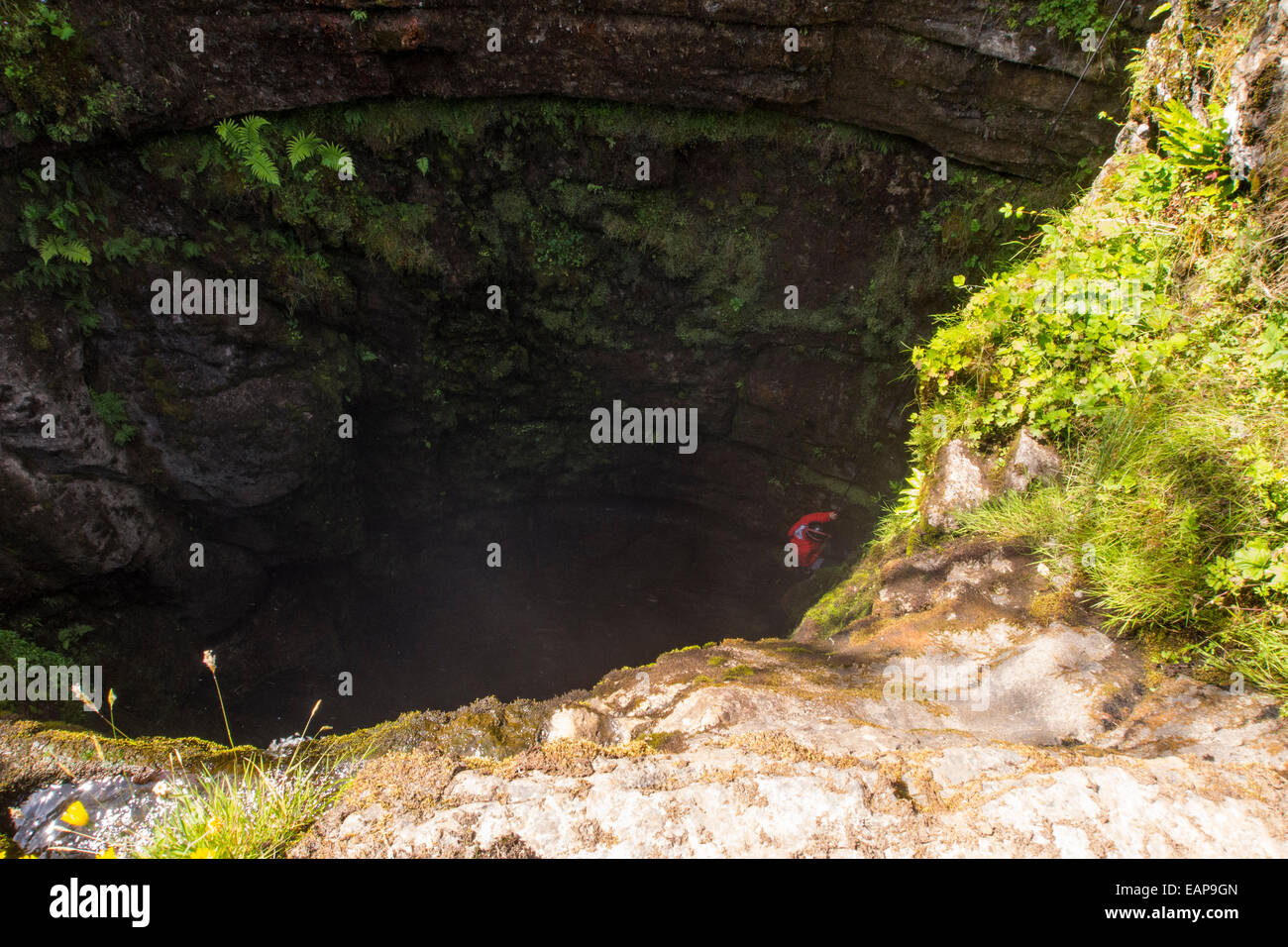 Un speleologo scende la famosa schiusi Gill grotta sul Ingleborough nel Yorkshire Dales, UK. Esso presenta un enorme caverna e la discesa più lunga di qualsiasi cascata nel Regno Unito, a circa 300 metri. Foto Stock