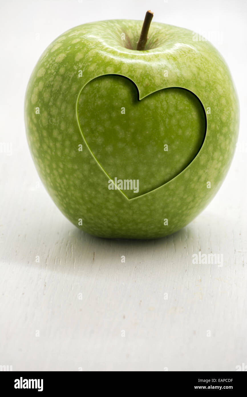 Verde mela con cuore intagliato, concettuale salute e benessere Foto Stock