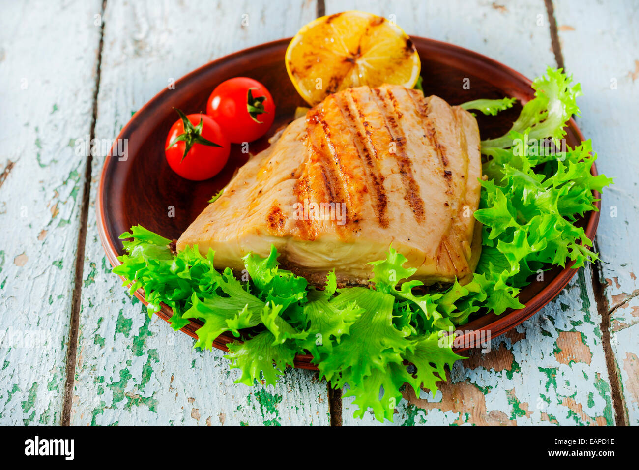 Grigliata di pesce di filetto con limone e pomodori ciliegia Foto Stock
