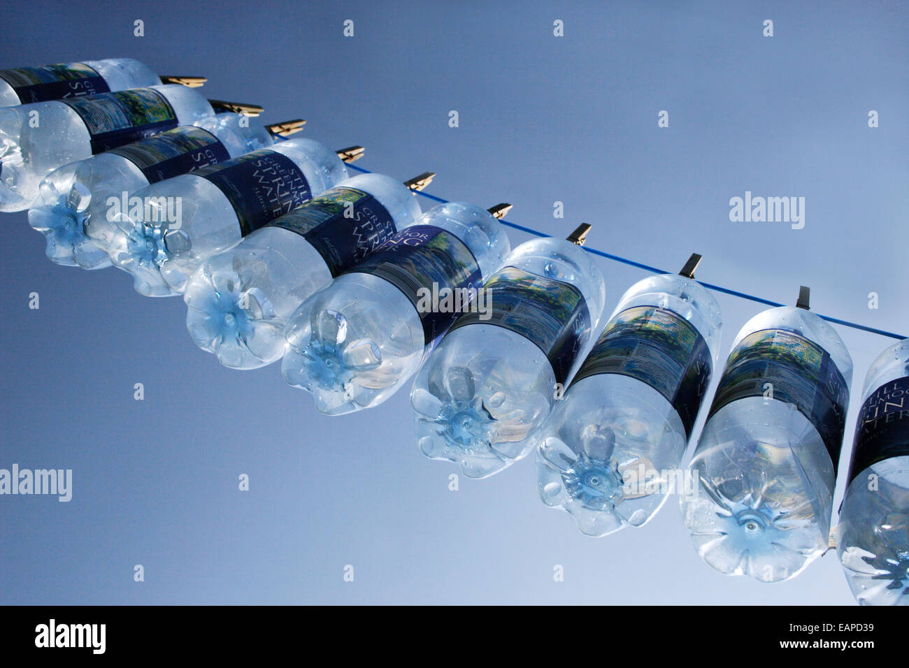 Molla in plastica bottiglie di acqua appesa sulla linea Foto Stock