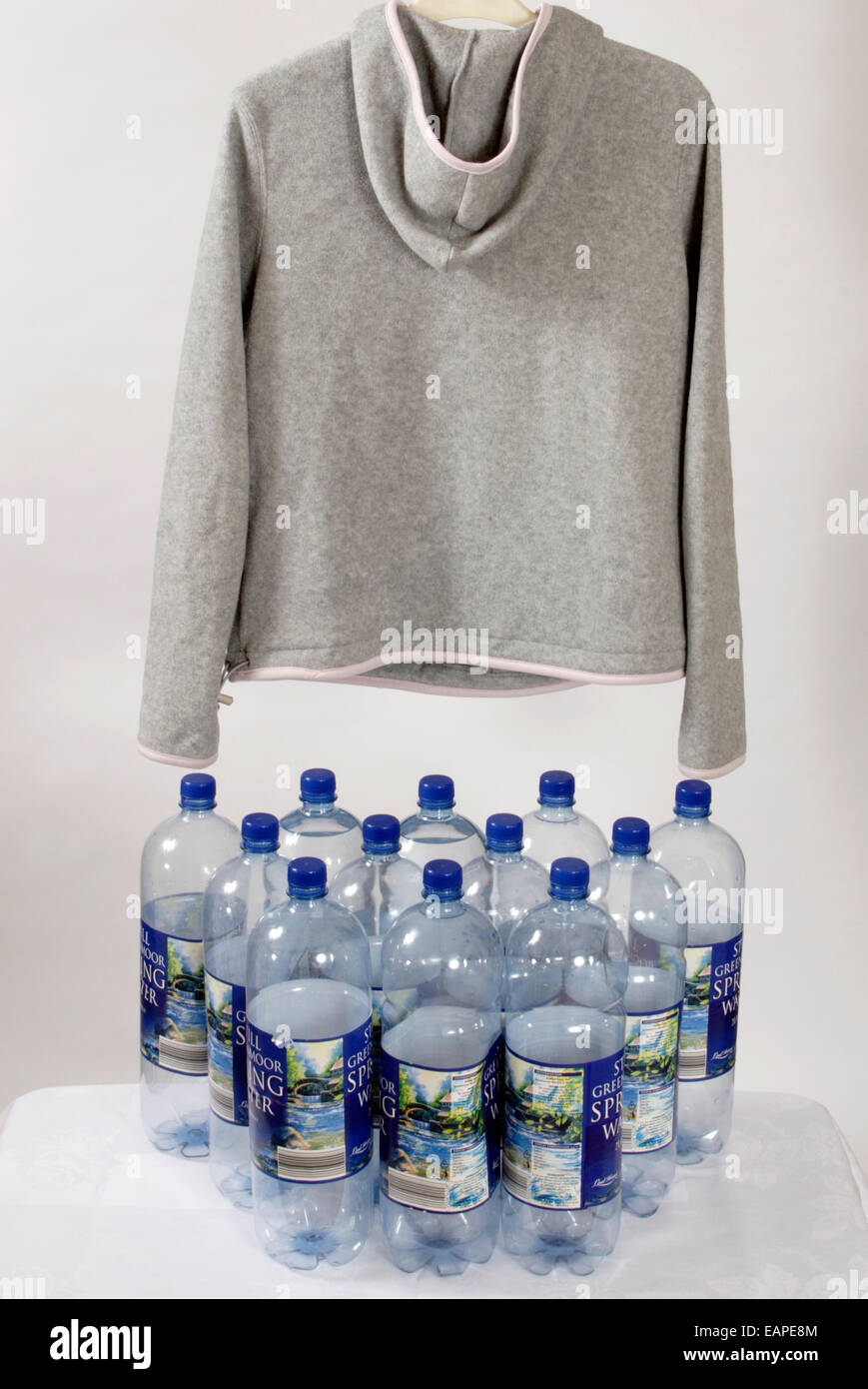 Studio shot in vello grigio sport con cappuccio alto appeso sopra dodici bottiglie di plastica Foto Stock