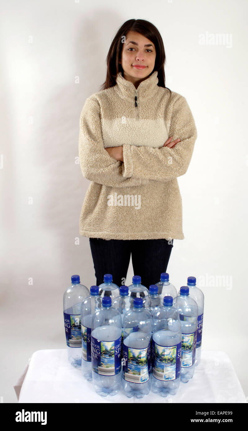 Ragazza indossando giacca in pile con permanente 12 di plastica grandi bottiglie d'acqua, illustrante prende 12 bottiglie per fare 1 pile Foto Stock