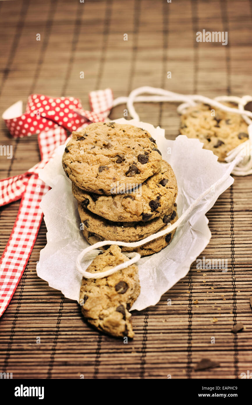 I cookies, aggiungete pezzetti di cioccolato sulla tovaglia bambù rustico, nastro rosso Foto Stock