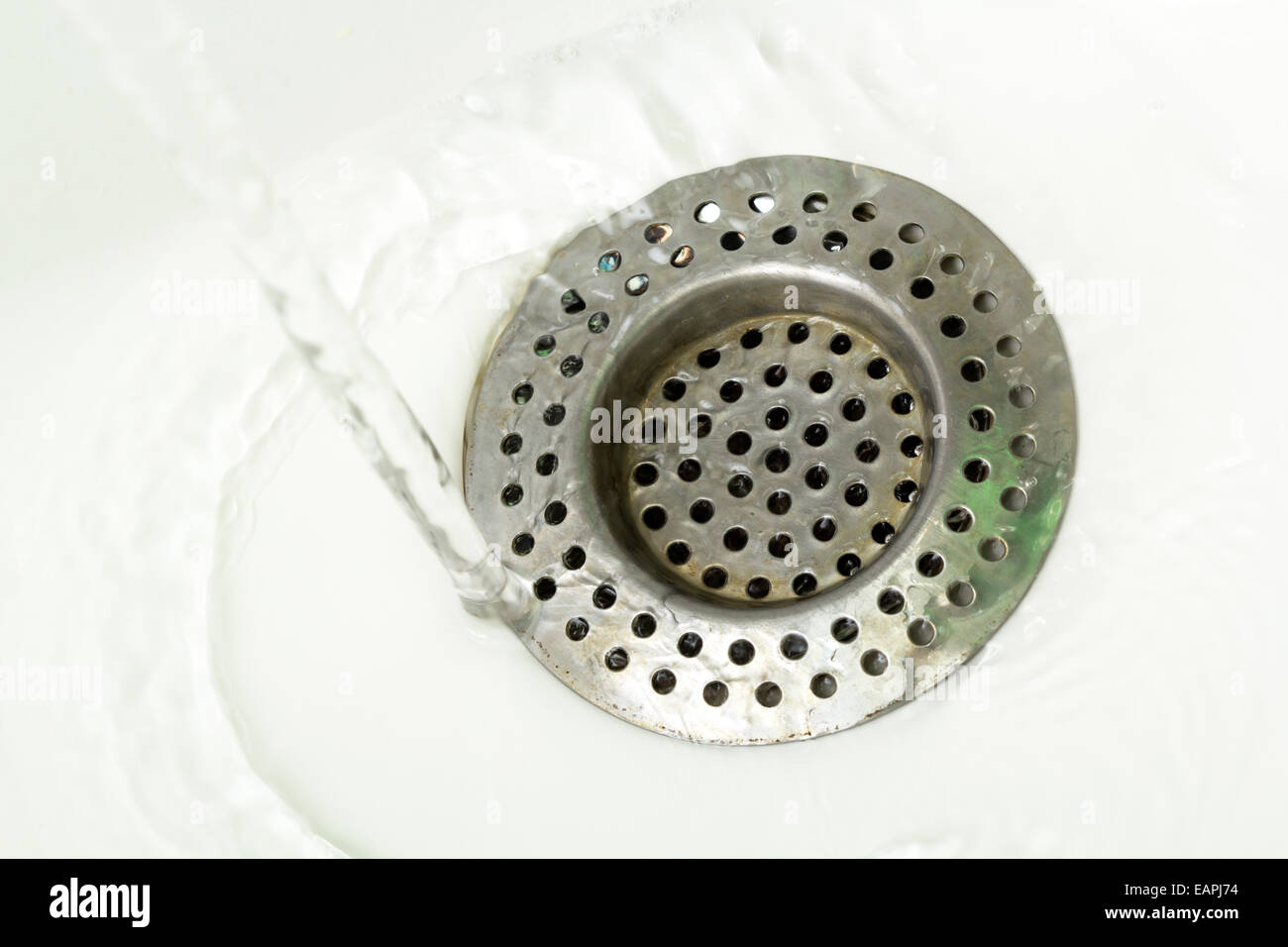 Esecuzione di acqua di rubinetto in un lavandino nello scarico Foto Stock