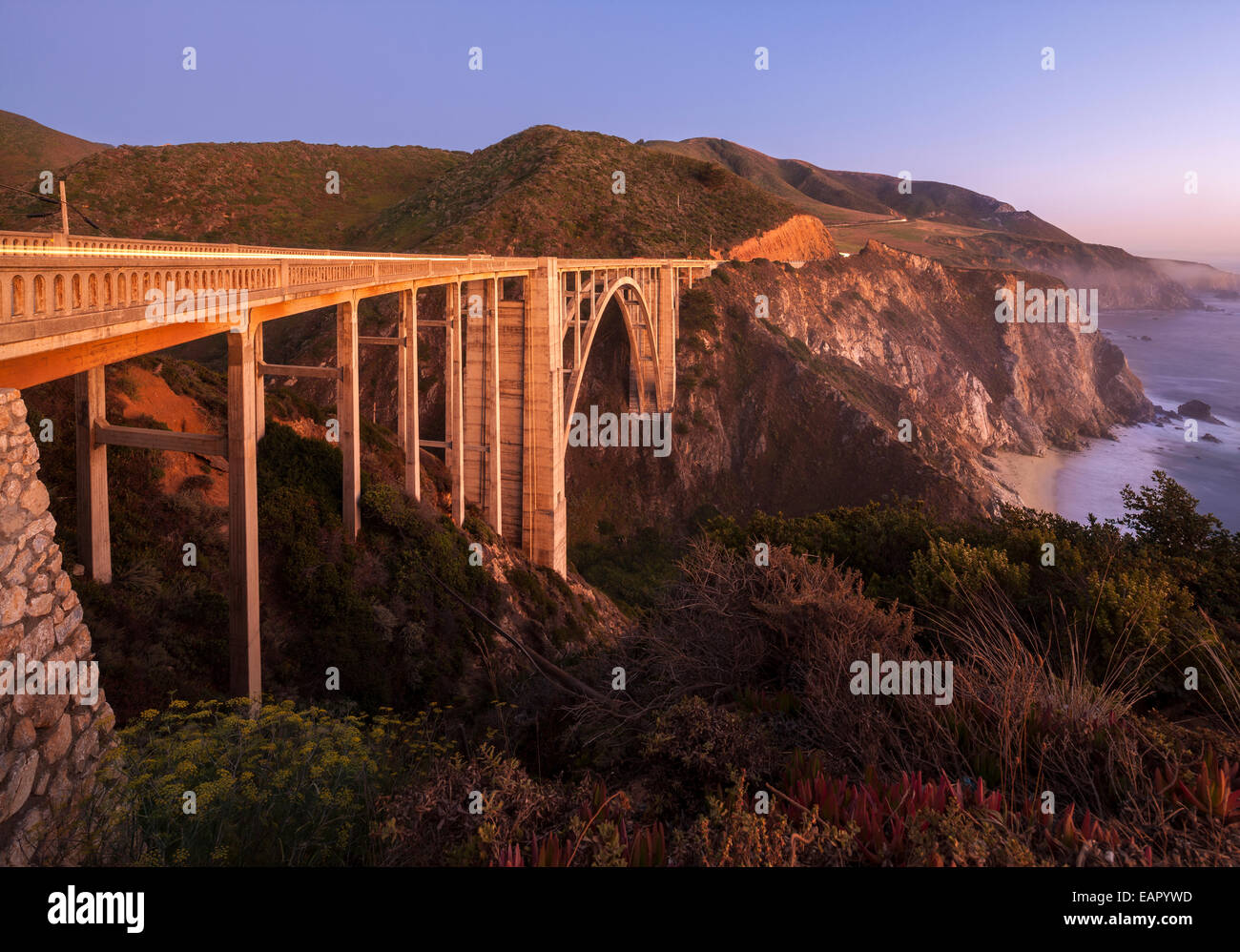 Bixby Bridge Pacific Coast Highway Big Sur in California. Bixby Creek Canyon Bridge con il litorale di striature di luce di automobili al tramonto. Foto Stock