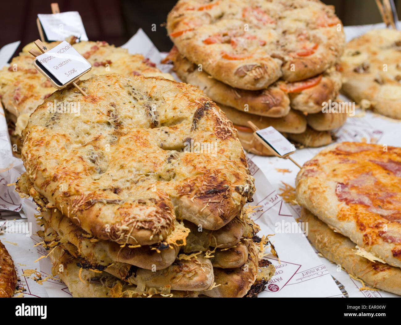 Pizza di pane, la cipolla e le acciughe. Un display di piccole pagnotte di pane condito come esotica pizze gourmet al mercato del venditore di tabella Foto Stock