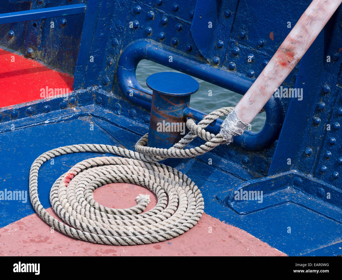 La corda avvolta sul ponte. Ordinatamente una linea a spirale sul ponte di un vecchio ferro da stiro tour in barca. Molti strati di vernice blu mostrano. Geo Foto Stock