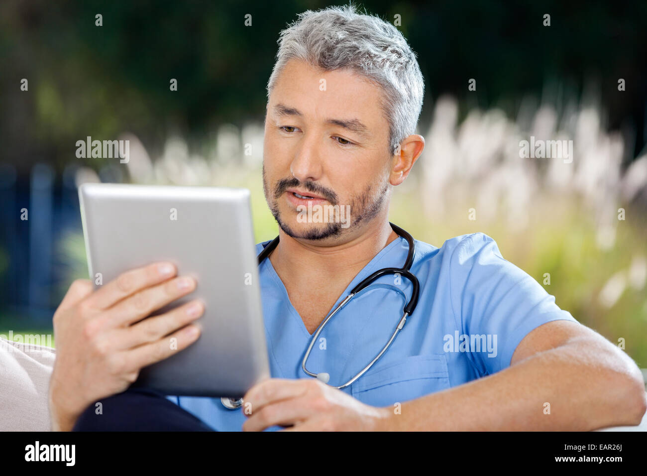 Custode maschio utilizzando un tablet PC mentre è seduto Foto Stock