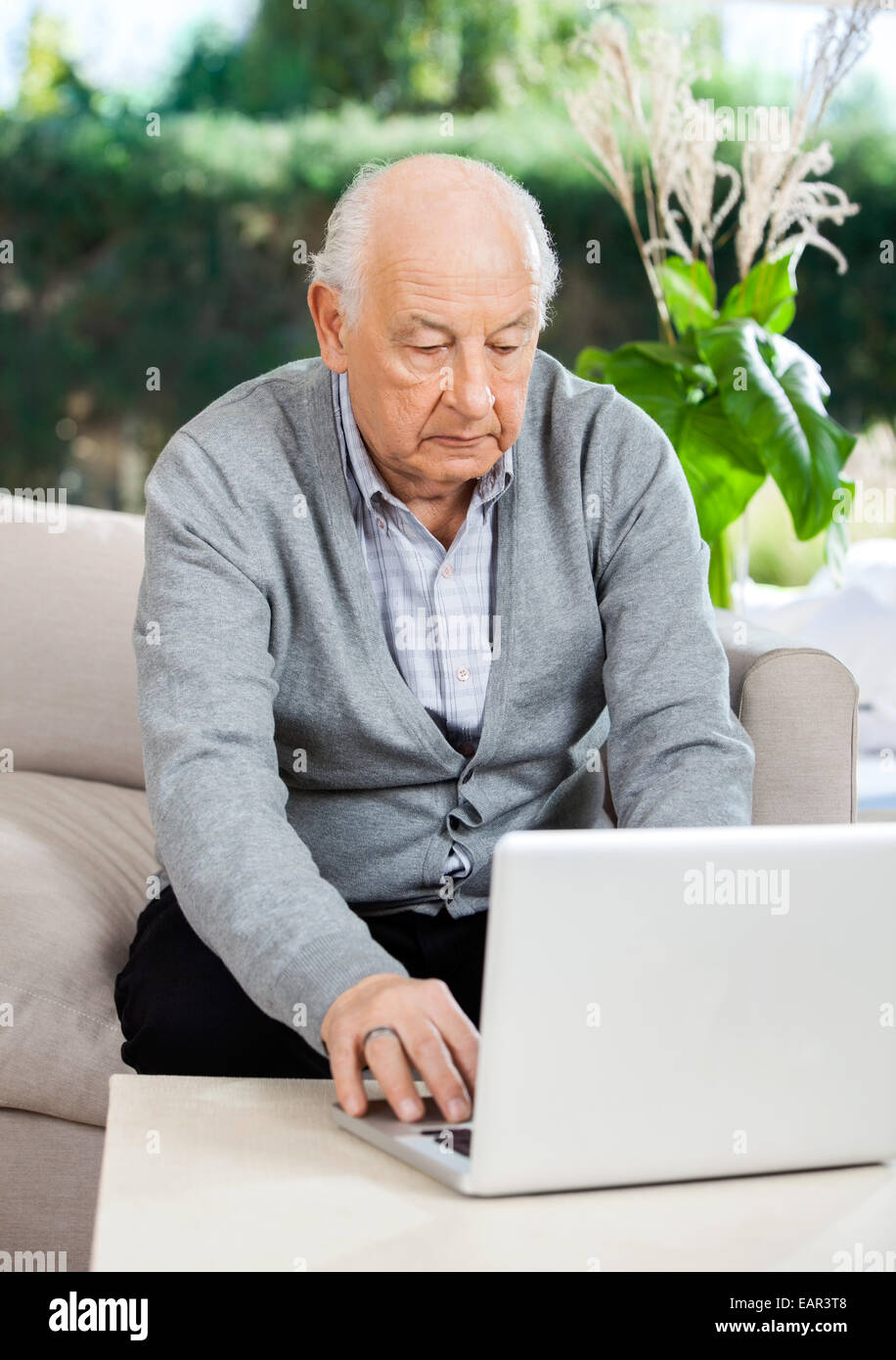 Senior uomo utilizzando computer portatile presso la casa di cura portico Foto Stock