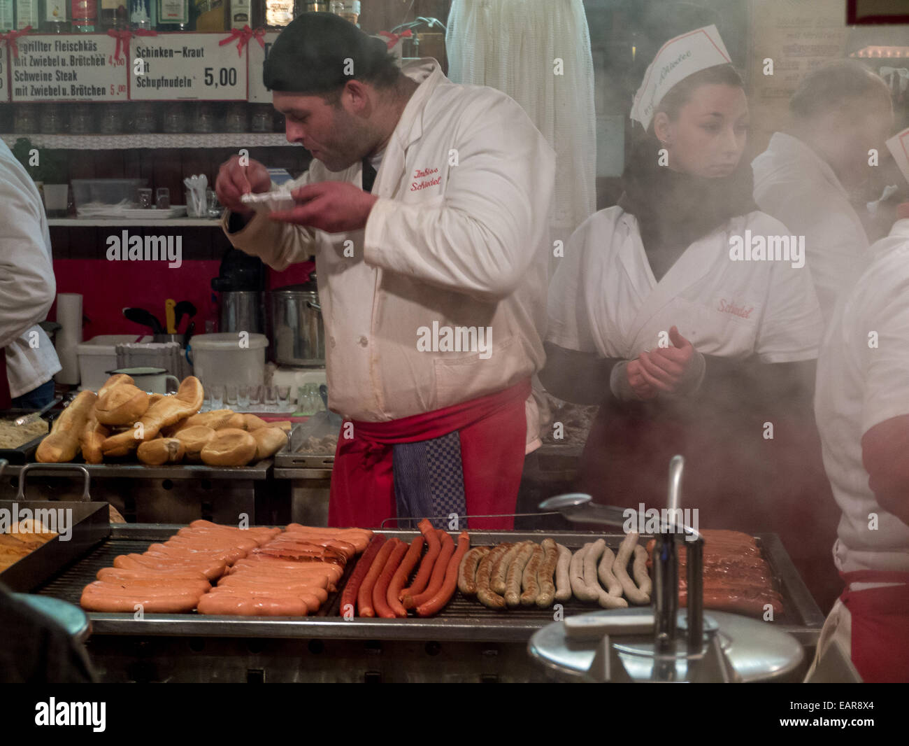 I cuochi preparare e servire le salsicce a un mercato di Natale in Germania Foto Stock