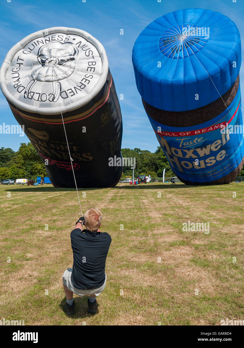 Una mongolfiera è conformato come una birra Guinness può con un gestore trattenendolo con una fune durante il gonfiaggio Foto Stock