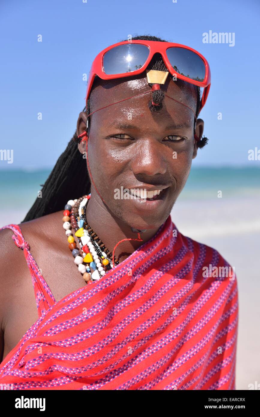 Giovane uomo Masai indossando vestiti tradizionali e occhiali da sole sulla spiaggia, Dongwe Beach, Dongwe, Zanzibar, Tanzania Foto Stock