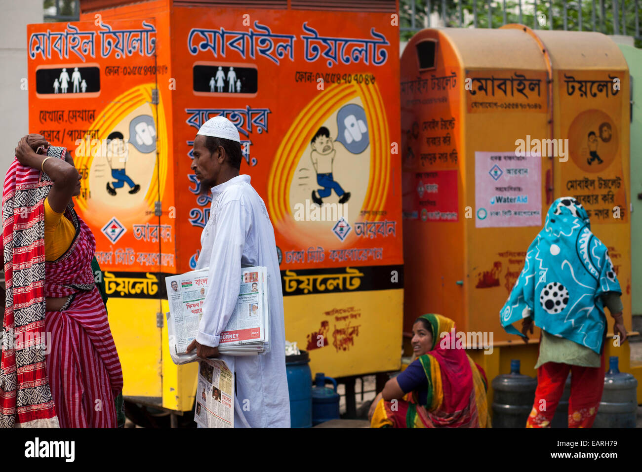 Una carta saller facendo conversazione con wc cleaner infront di Mobile itinerante wc accanto alla strada di Dhaka. Inadeguate condizioni sanitarie in Asia del Sud conduce a un certo numero di malattie tra cui la diarrea. Ma la più drammatica conseguenza di aprire la defecazione è l epidemia di Ebola in Africa occidentale, un' organizzazione mondiale della sanità (OMS) relazione detto questo in una relazione pubblicata alla vigilia della "Giornata mondiale dei servizi igienici". L'OMS stima che ogni dollaro speso per l igiene dà un ritorno di 9 dollari US. Si stima inoltre che l'India la perdita e il PIL è stato 6,4 per cento a causa di scarsa igiene. Il che nella sua relazione ha detto Foto Stock