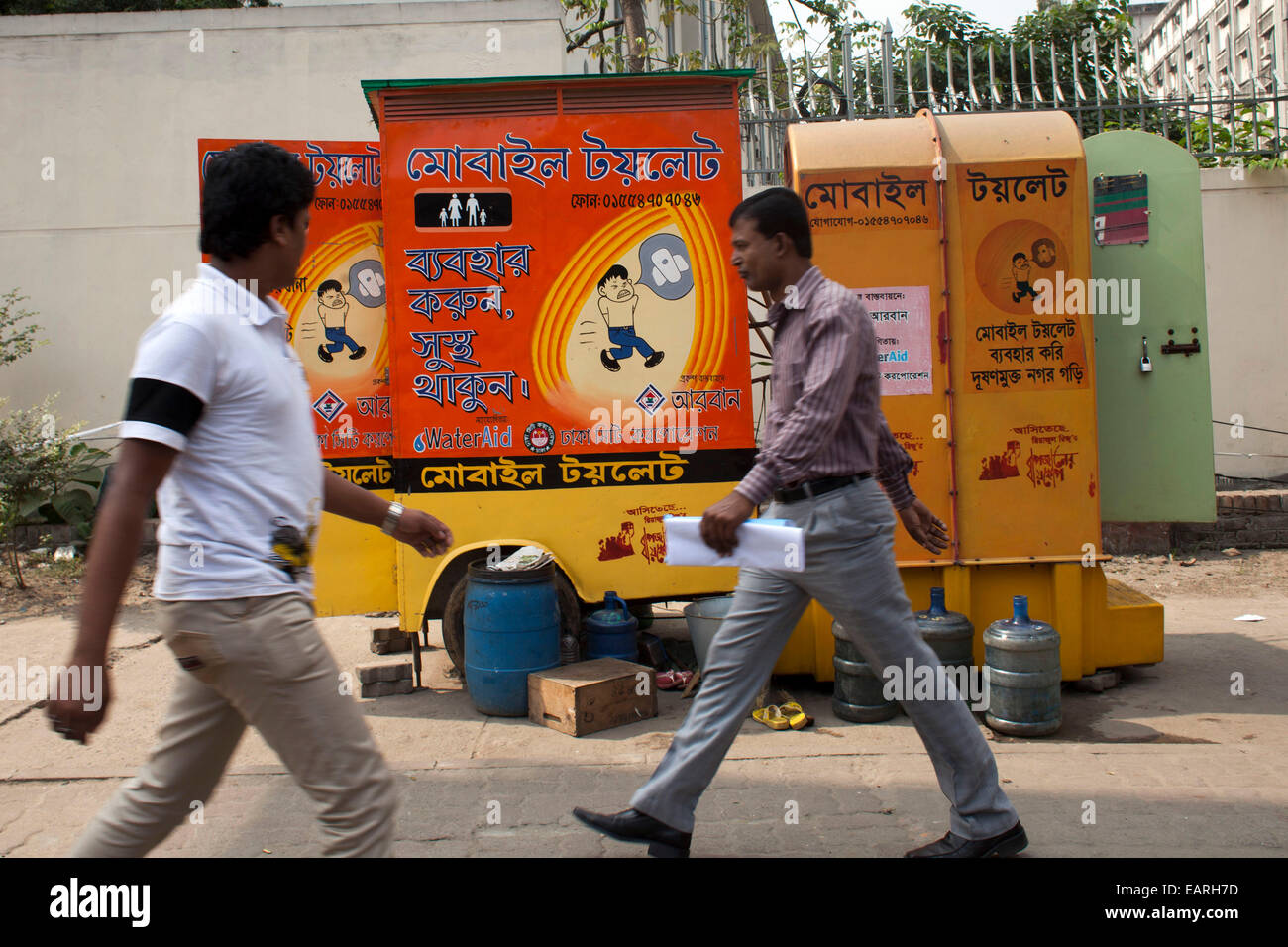 La gente camminare sulla strada accanto a itineranti wc Mobile a Dhaka. Inadeguate condizioni sanitarie in Asia del Sud conduce a un certo numero di malattie tra cui la diarrea. Ma la più drammatica conseguenza di aprire la defecazione è l epidemia di Ebola in Africa occidentale, un' organizzazione mondiale della sanità (OMS) relazione detto questo in una relazione pubblicata alla vigilia della "Giornata mondiale dei servizi igienici". L'OMS stima che ogni dollaro speso per l igiene dà un ritorno di 9 dollari US. Si stima inoltre che l'India la perdita e il PIL è stato 6,4 per cento a causa di scarsa igiene. Il che nella sua relazione ha detto che il Sud Asia rischia di perdere il suo obiettivo di Foto Stock