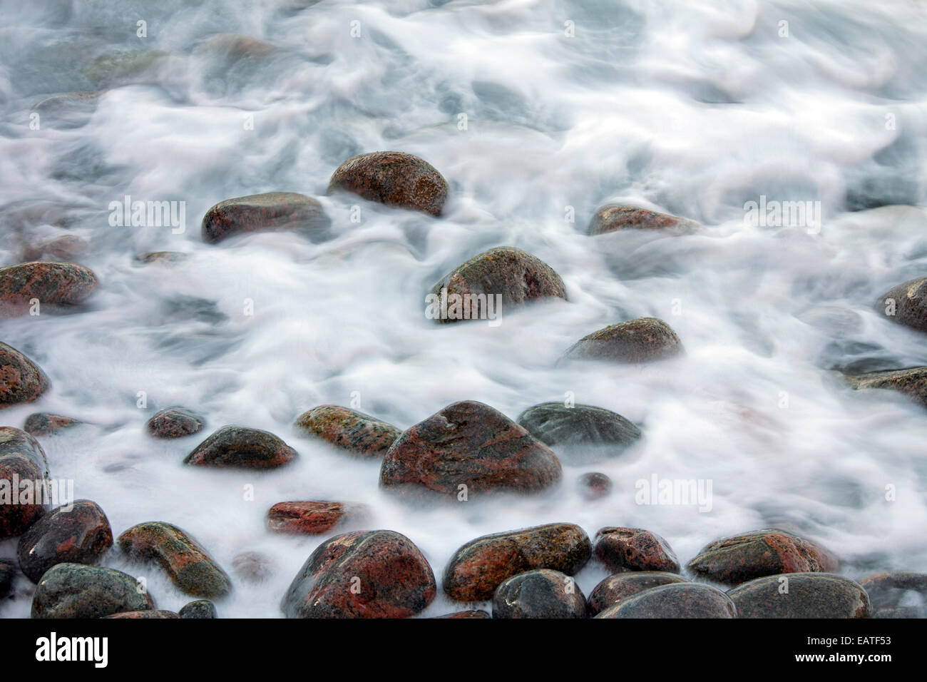 Close up di ciottoli colorati coperti da onda sulla spiaggia di ciottoli a Rising Tide Foto Stock