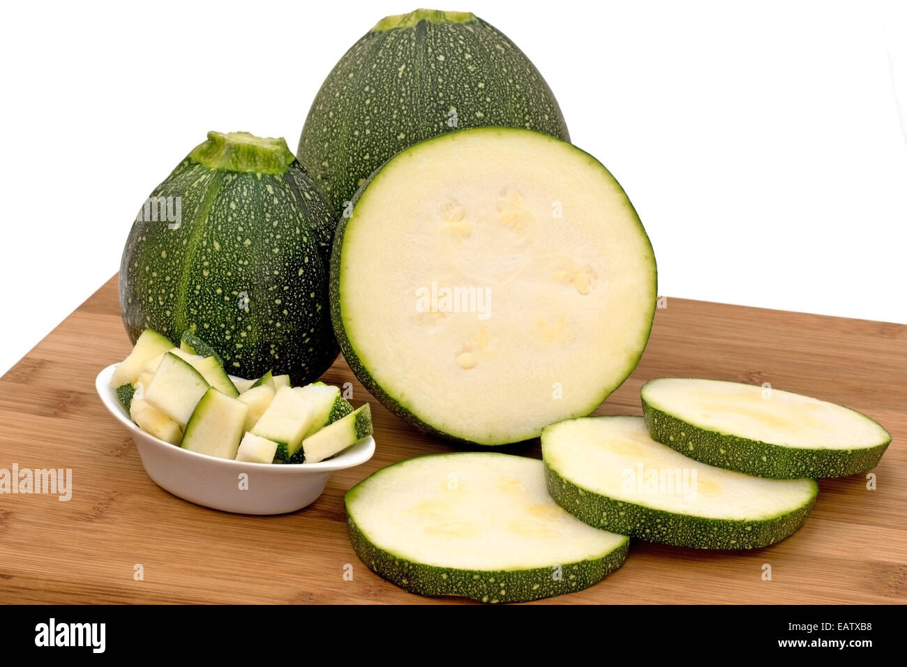 Round Zucchine,le zucchine tagliate a fette e tagliate su un pannello di legno con uno sfondo bianco Foto Stock