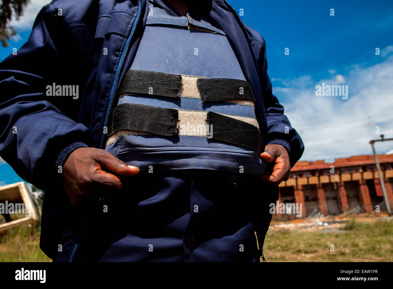 Una guardia di sicurezza indossa un bullet proof vest come egli si trova sul dovere al di fuori abbandonata miniera d'oro di Durban del profondo sottostazione. Giorni Foto Stock