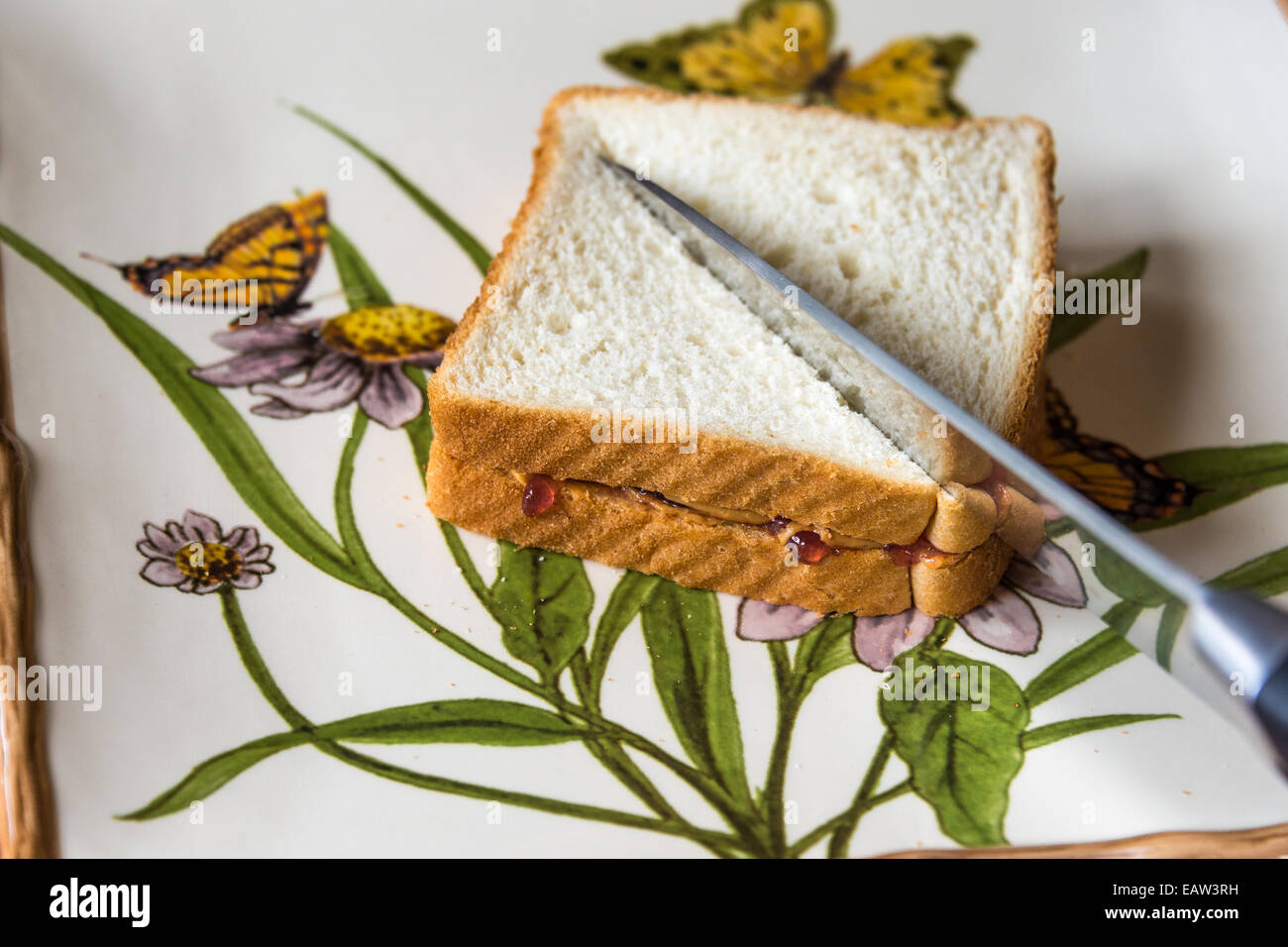 Burro di arachidi pane la piastra di diffusione di taglio dei coltelli di taglio a metà bianco gelatina di sandwich Foto Stock