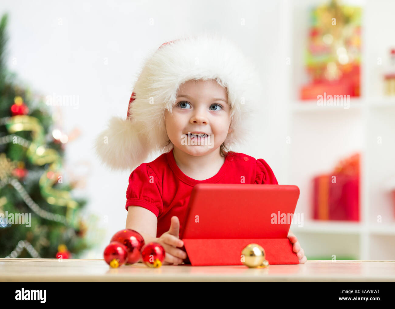 Kid ragazza nel cappello di Natale con i tablet pc Foto Stock