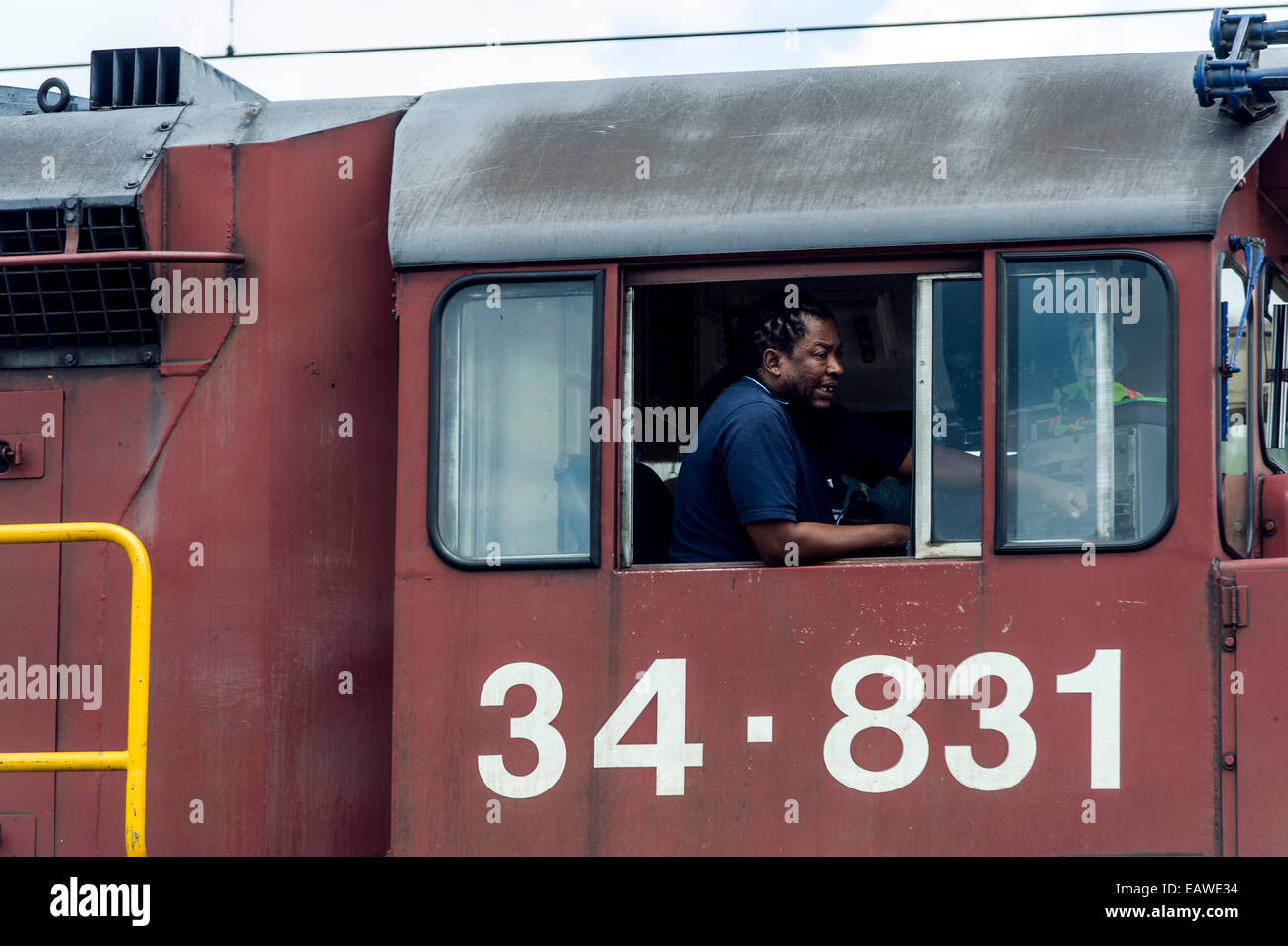 Un macchinista guida una locomotiva diesel su un passaggio a livello. Foto Stock