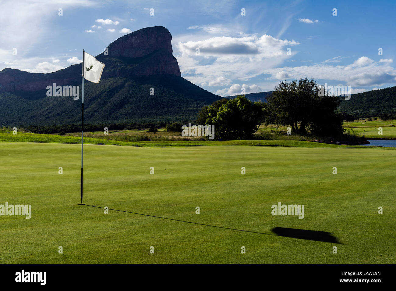 Un flag si appoggia nel bicchiere su un golf sotto le frastagliate cime delle montagne. Foto Stock