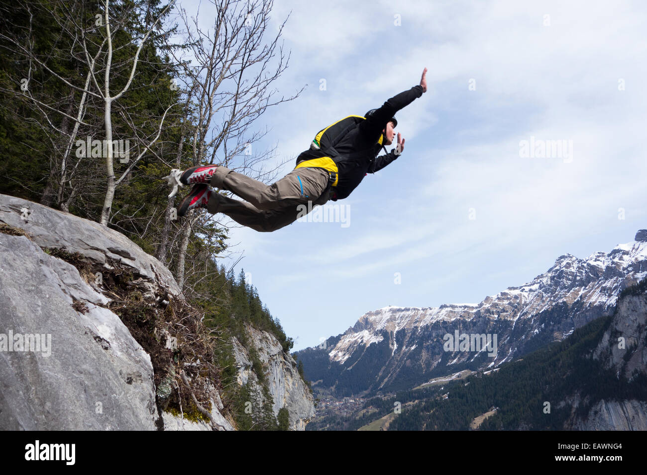 Ponticello di base sta uscendo da una rupe verso il basso nella profonda valle. In tal modo egli è entro una wingsuit a tariffa volare lontano dalla roccia. Foto Stock