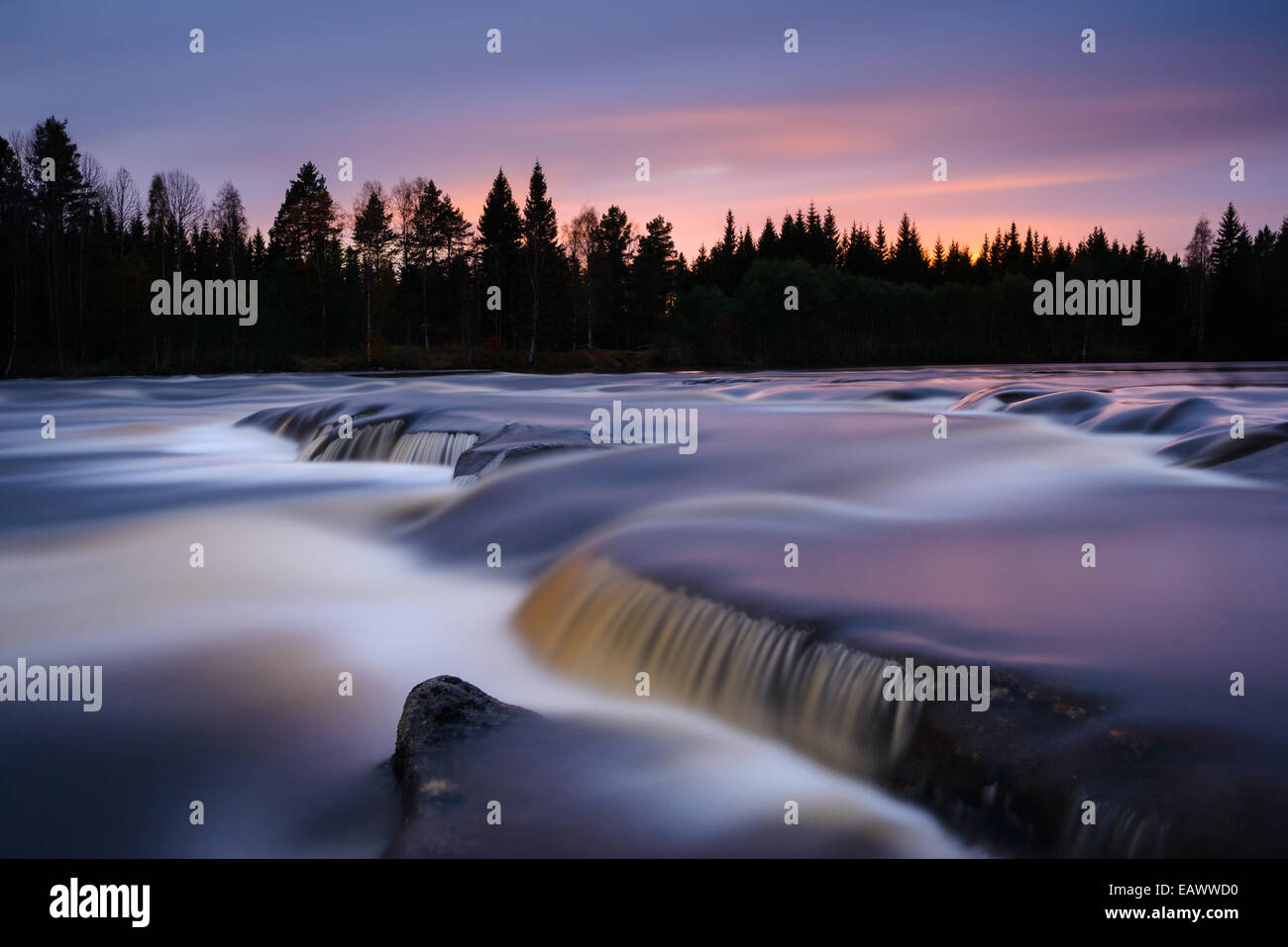 Misty acqua correndo sulle rocce al tramonto Foto Stock