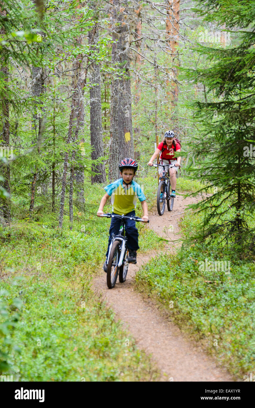 Madre e figlio equitazione mountain bike giù per un sentiero di bosco Foto Stock