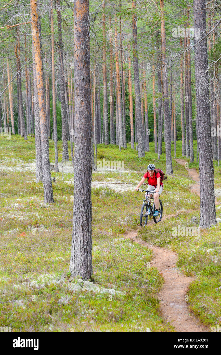 Equitazione donna la sua bici giù per un sentiero di bosco Foto Stock