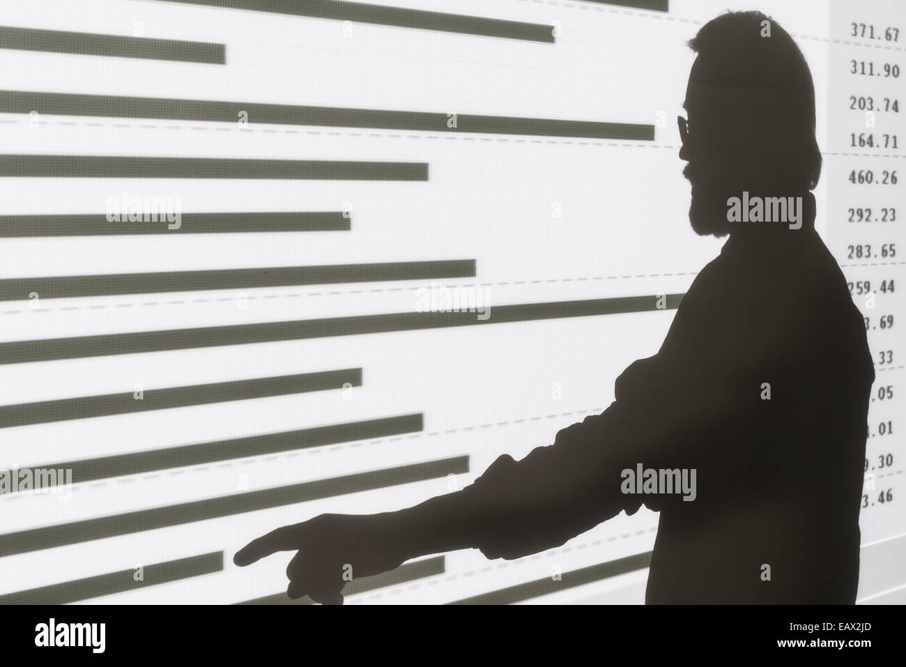 Silhouette di un uomo rivolto a un grafico a barre di proiezione Foto Stock