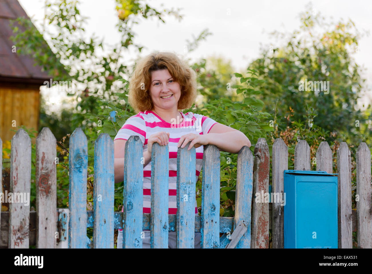 Donna di mezza età è alle porte country house Foto Stock