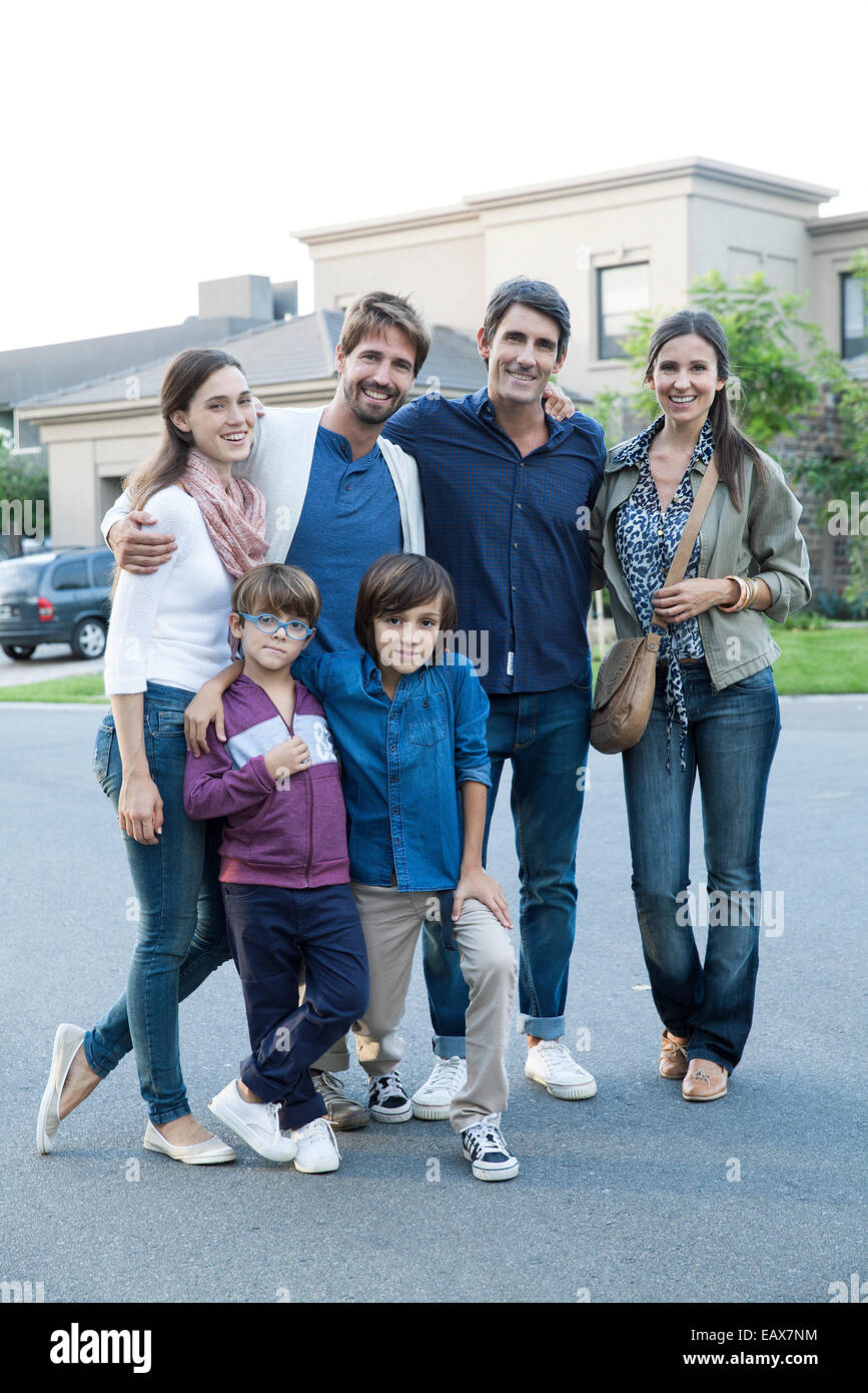 La famiglia in posa insieme sulla strada suburbana, ritratto Foto Stock