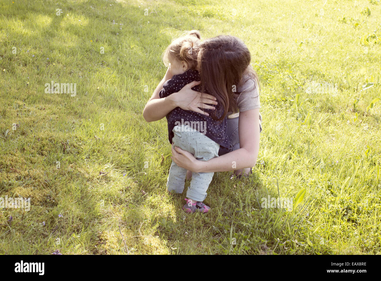 Madre abbracciando bambina all'aperto Foto Stock