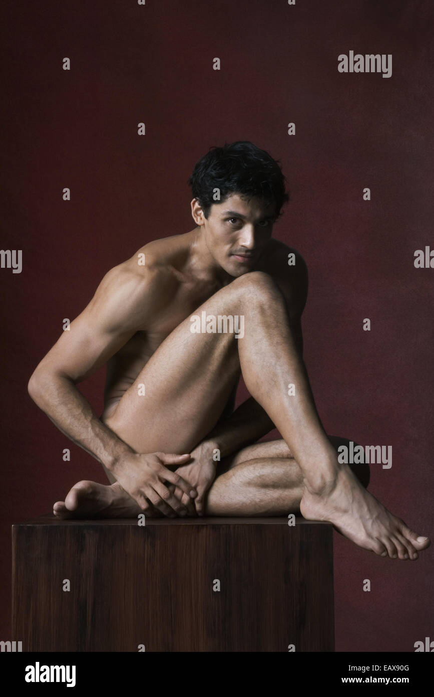 Luomo nudo seduto con la testa appoggiata sul ginocchio a piena lunghezza ritratto Foto Stock