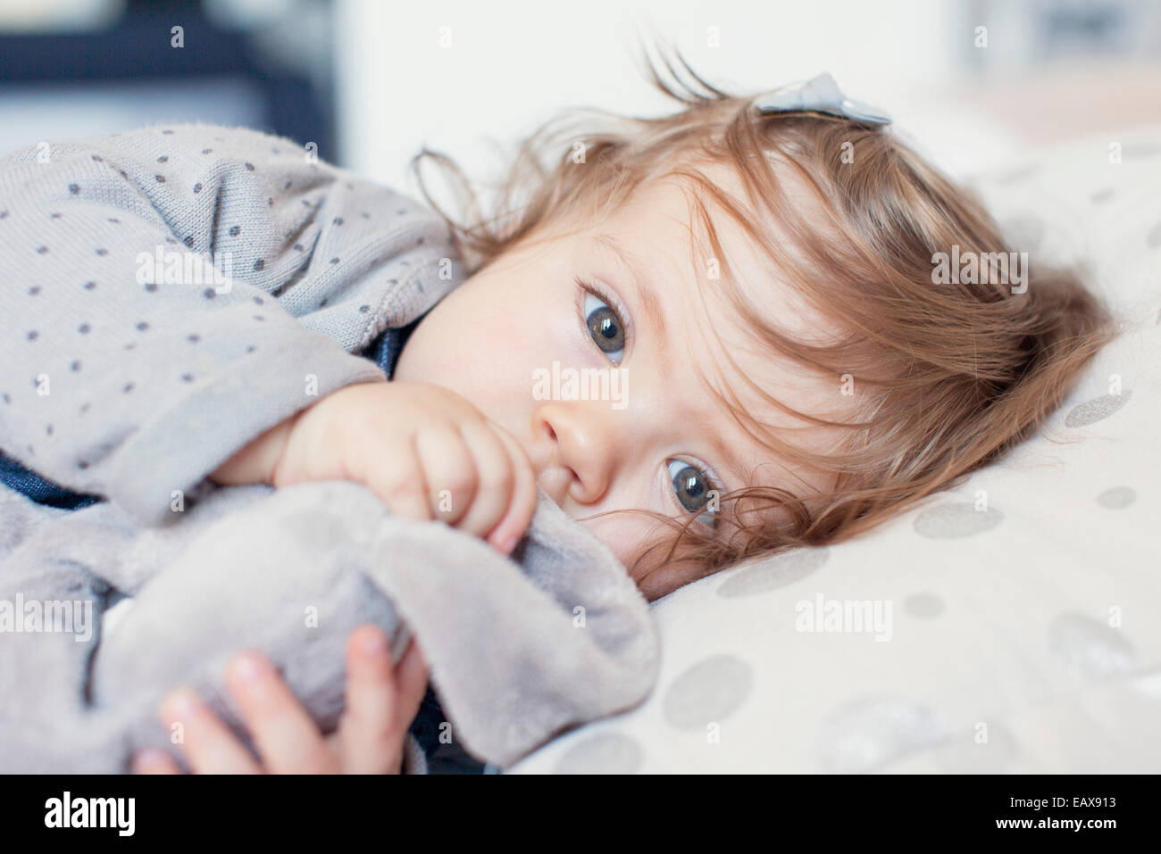 Baby girl sdraiato, aspirando il pollice, ritratto Foto Stock