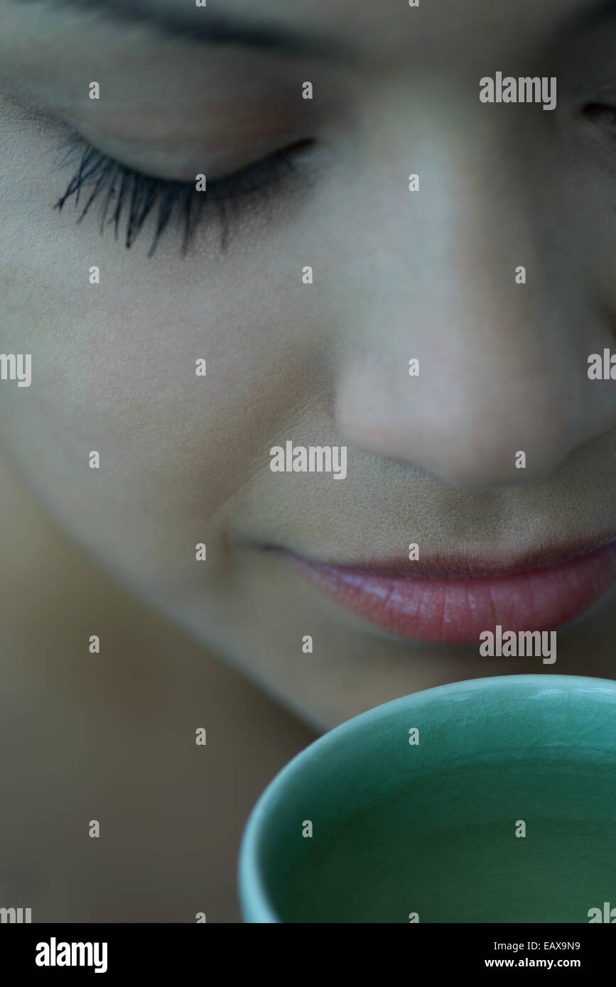 Donna odore di tazza di tè con gli occhi chiusi, close-up Foto Stock