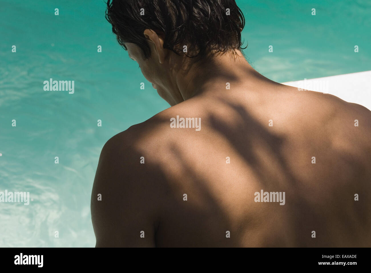 Uomo che guarda alla piscina, vista posteriore Foto Stock