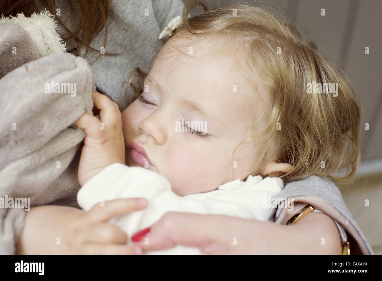 Baby ragazza dorme nella madre di braccia, ritagliato Foto Stock