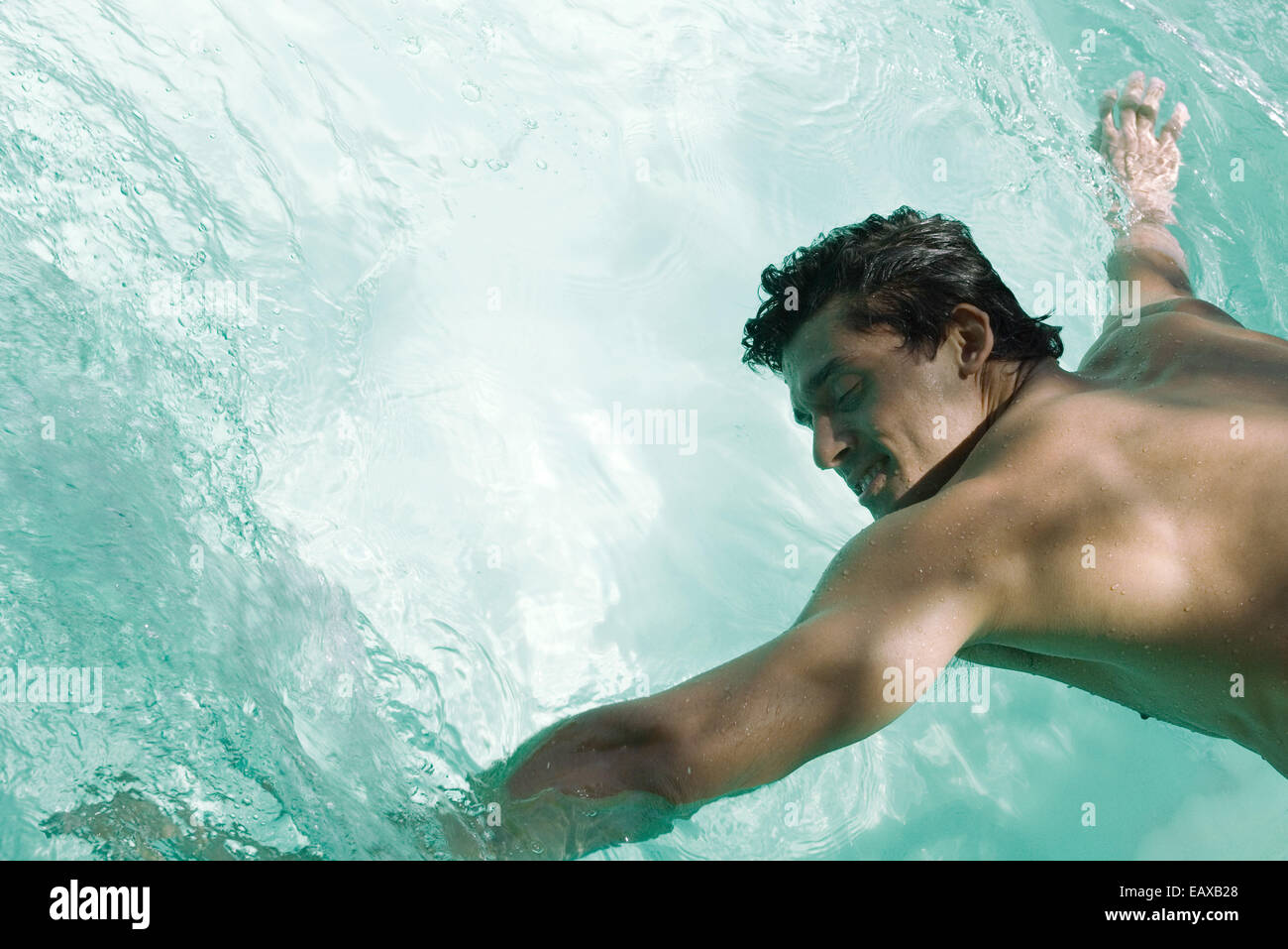 Uomo appoggiato sulla piscina, braccia in acqua Foto Stock