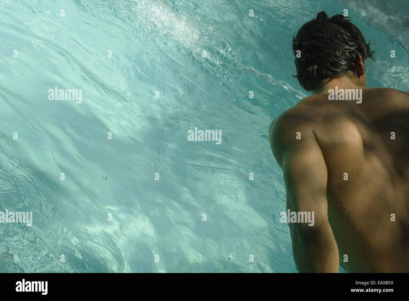 Uomo appoggiato sulla piscina, vista posteriore Foto Stock