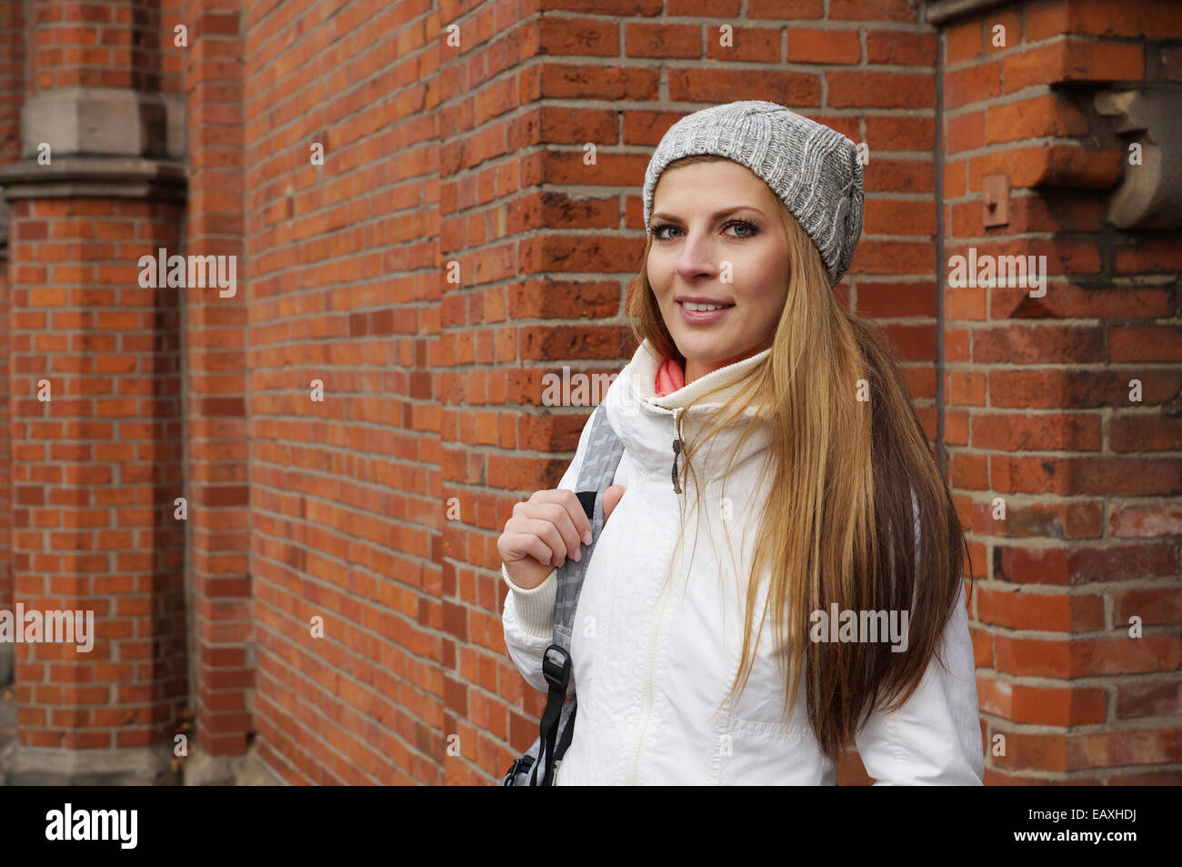 Outdoor ritratto di una giovane donna che indossa cappello di lana di fronte all edificio di mattoni rossi Foto Stock