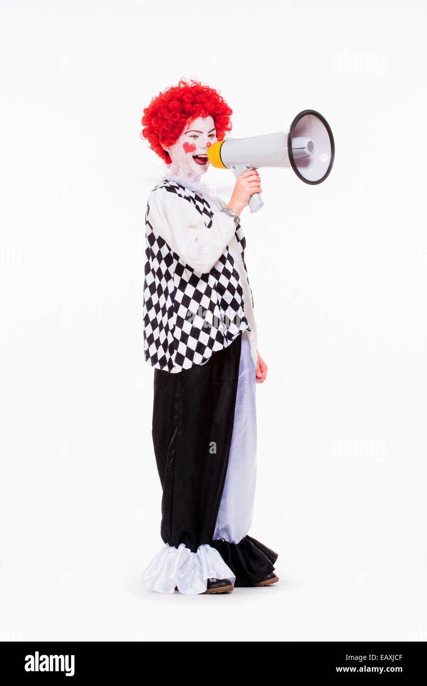 Poco Clown in rosso parrucca e trucco usando megafono. Foto Stock