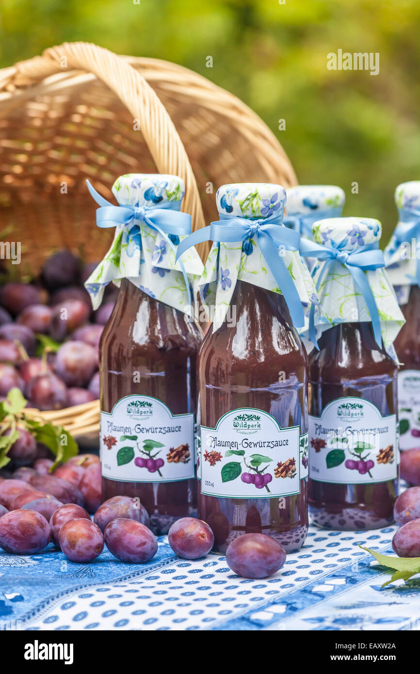 Bottiglie con il piccante salsa di prugne sul tavolo da giardino Foto Stock