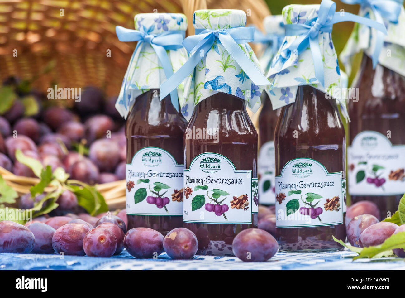 Bottiglie con il piccante salsa di prugne sul tavolo da giardino Foto Stock