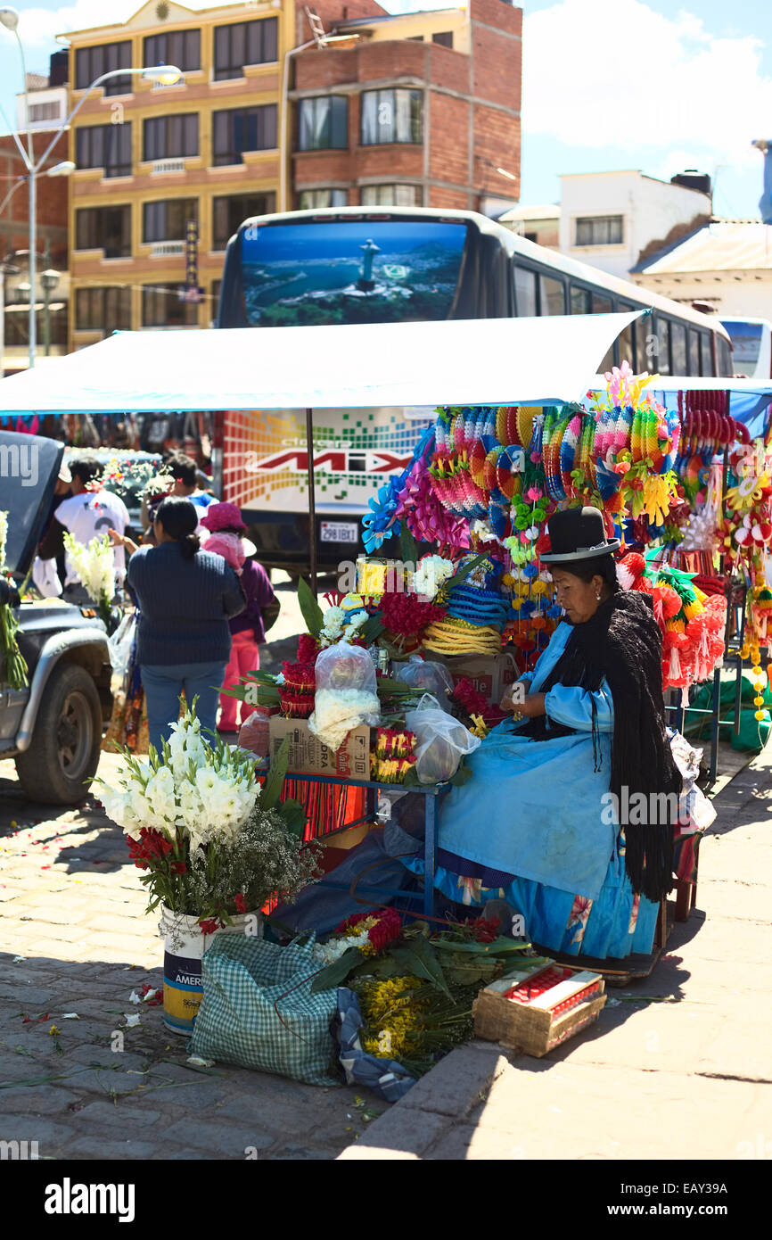 Donna vestito in abiti tradizionali ornamenti di vendita per la benedizione delle vetture in Copacabana, Bolivia Foto Stock