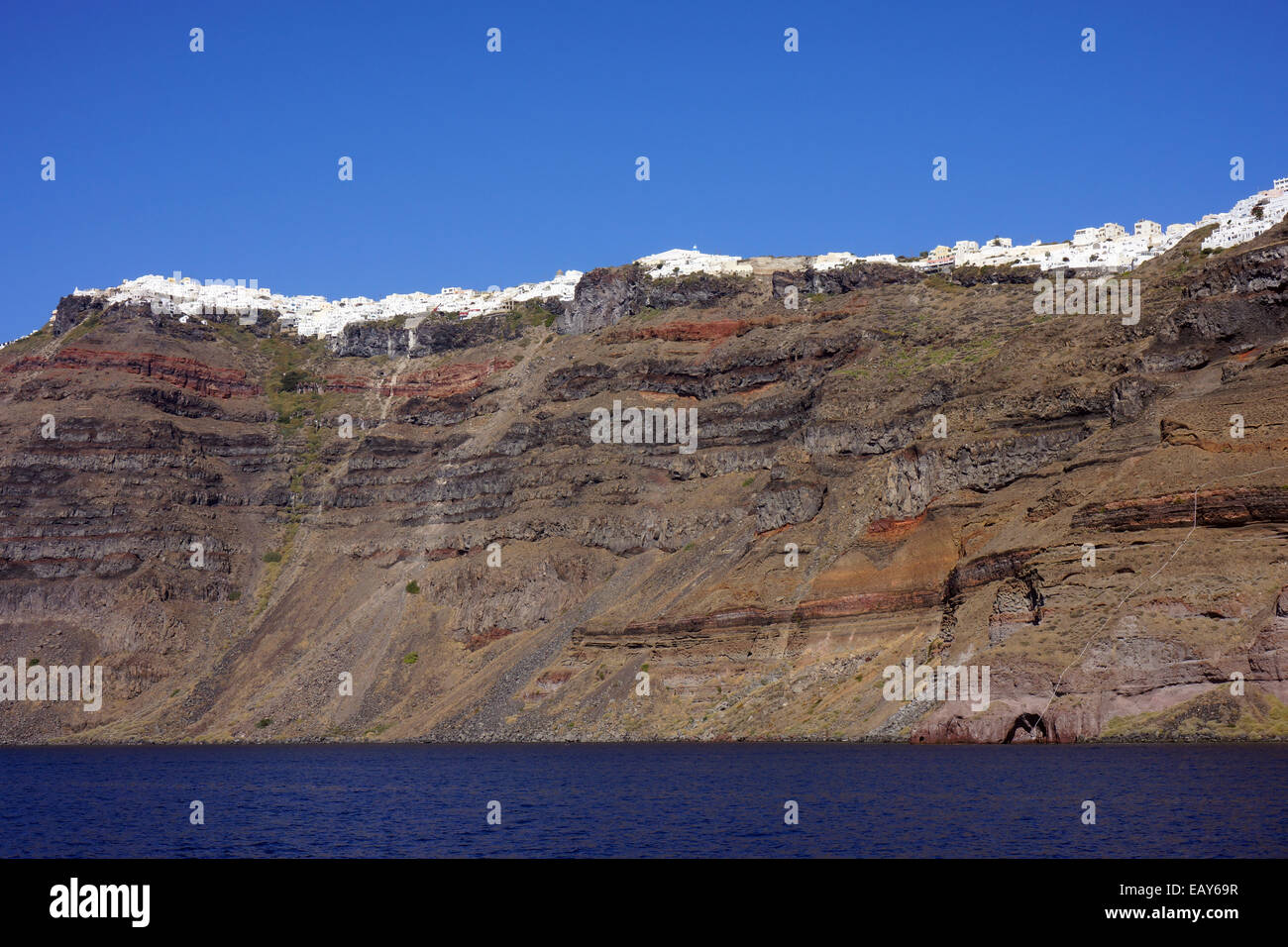 Casa bianca sul bordo della caldera, il cratere vulcanico, Santorini, con strati di lava vulcanica rock, Grecia Foto Stock