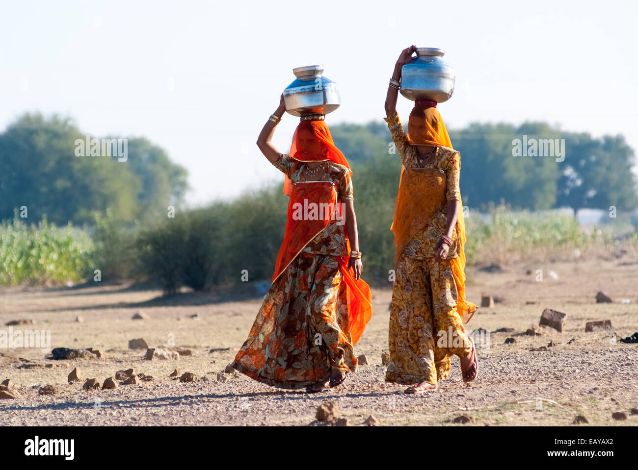 Le donne lo sforzo di una pentola di acqua sulla loro testa per prelevare acqua da una fonte naturale Foto Stock