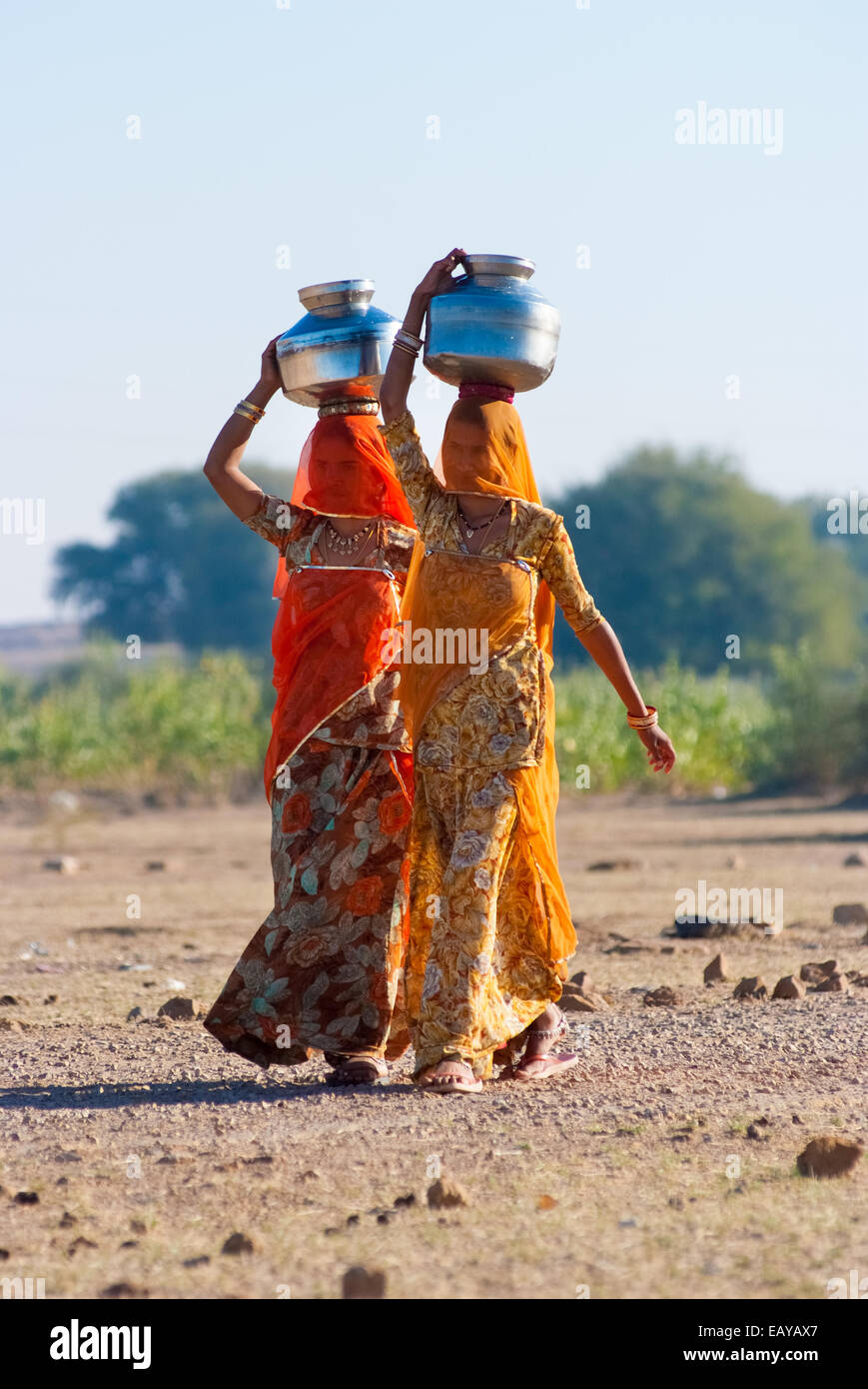 Le donne lo sforzo di una pentola di acqua sulla loro testa per prelevare acqua da una fonte naturale Foto Stock