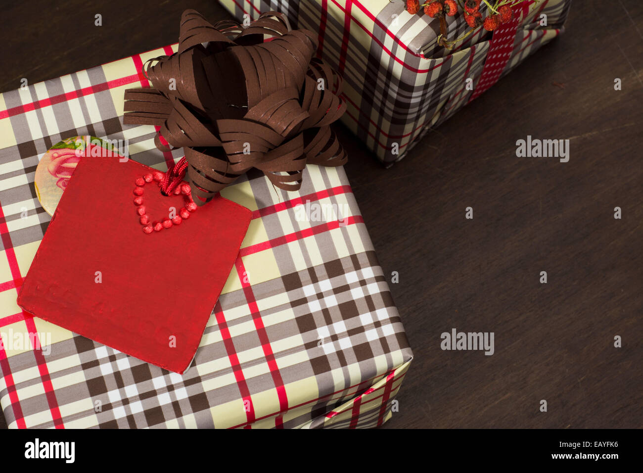 Regali avvolti in carta a scacchi e punteggiata nastro con stella rossa etichetta su sfondo di legno Foto Stock